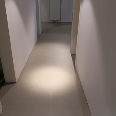 Heller Flur mit LED-Beleuchtung und weißen Wänden, Bodenbelag in neutralen Tönen.