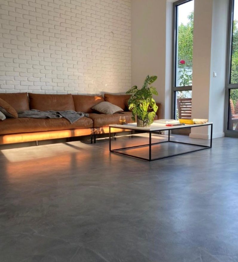 Helles, modernes Loft mit großen Fenstern, minimalistische Möbel und einem Mikrozement Boden im Industriell Design