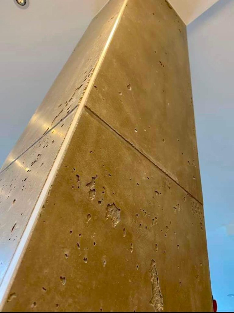Ein gehobelter Betonpfeiler mit glatter goldener Oberfläche in Innenraum.