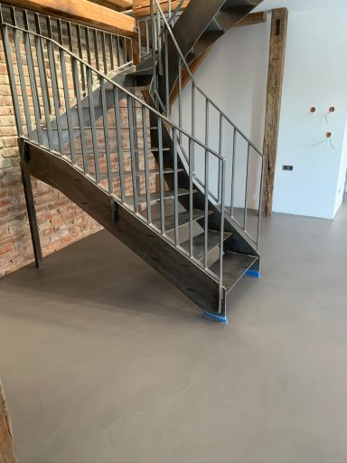 Moderne Metalltreppe mit Holzgeländer in neuem, lichtdurchflutetem Raum.
