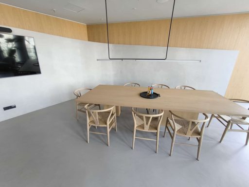 Moderne Besprechungsräume mit großem Tisch und Holzstühlen, TV an der Wand.