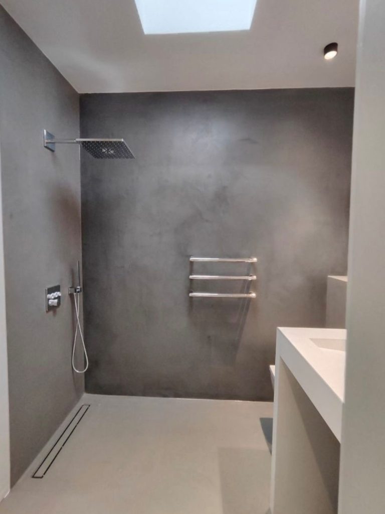 Moderne Badezimmeransicht mit grauen Wänden, Dusche und handtuchhalter.
